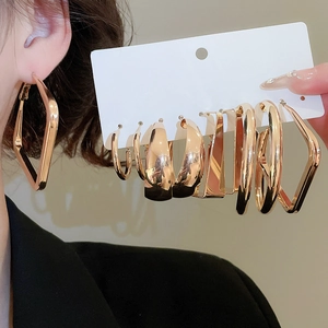 Detail view of gold geometric hoop earring set worn by a model in warm studio lighting