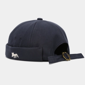 Detail of navy blue docker hat featuring a small white fox embroidery and metal buckle