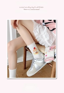 Détail de chaussettes blanches en coton avec broderies de gâteaux et cerises cartoon