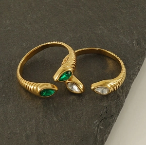 Detailed view of water-drop zircon rings with gold threaded band on grey stone