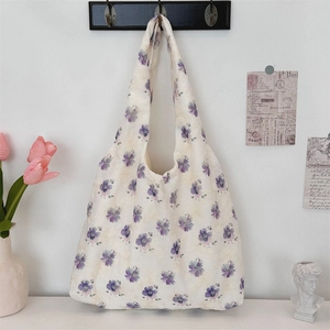 Detail of floral embroidery on a beige canvas tote bag hanging on a vintage wall hook