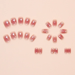 Close-up of pink gradient press-on nails with star patterns and small rhinestones