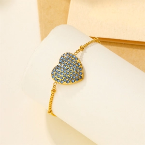 Detail of 18k gold heart bracelet with blue rhinestone micro-pave on cylindrical stand