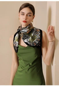 Close-up of silk scarf with botanical print styled with a green satin dress and gold jewelry