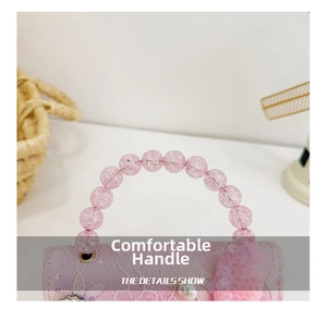 Dettaglio borsa rosa in pizzo con manico di perle e ali decorate con paillettes
