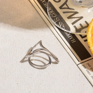 Detail of minimalist stainless steel ring with elegant wavy lines on textured background
