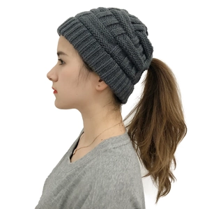 Detail of dark grey knitted ponytail hat showing the ribbed texture and top opening hole