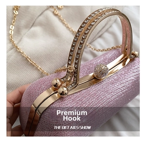 Detail of pink glitter evening clutch showing gold metal frame and rhinestone clasp