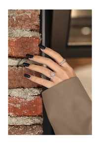 Detail of S925 silver beaded rings with pink stone on model hand with brick wall background