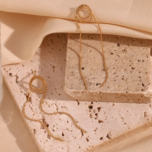 Macro detail of golden 18K plated spiral knot stud with long snake chain fringe tassels