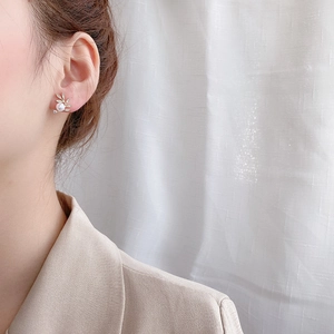 Leaf design gold earrings with micro-pave crystals and white pearl worn by a model