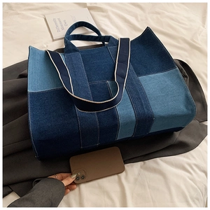 Detail of multi-tone denim tote bag featuring patchwork design and durable wide shoulder strap