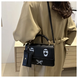 Close-up of black leather crossbody bag with skull print and gold hardware detailing