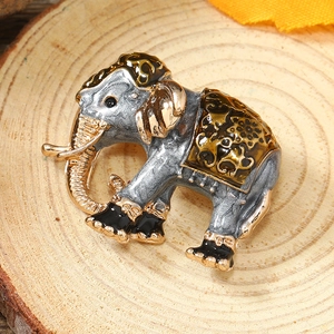 Detailed view of an elephant brooch with silver, gold, and black enamel on a wooden base