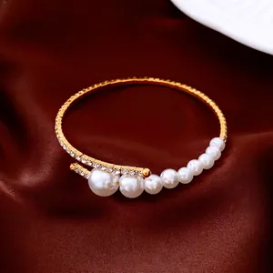 Elegant gold-tone open cuff bracelet featuring luminous pearls and sparkling accents