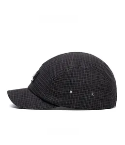 Detailed side view of a black plaid 5-panel camp cap with metal eyelets and a woven label