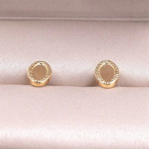 Detailed close-up of golden oval earrings with hammered texture in luxury jewelry box