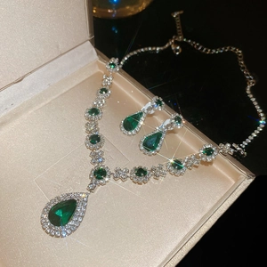 Macro shot of emerald green pear-cut crystal necklace and earrings in a luxury jewelry box