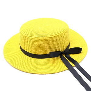 Détail du chapeau canotier en paille jaune avec ruban noir et nœud décoratif élégant