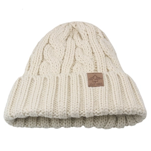Close-up of chunky cable knit beanie showing cream texture and brown leather label