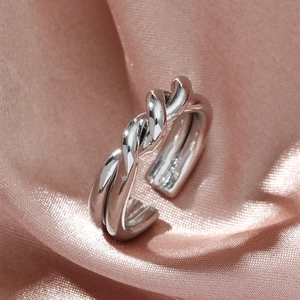Elegant silver twisted rope open ring on soft pink silk background for women