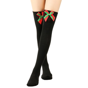 Detail of black over-knee socks featuring red and green Christmas bows on knit fabric