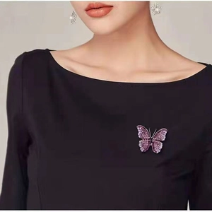Close-up of elegant butterfly brooch with purple crystals on black garment