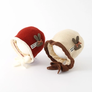 Winter knitted baby hat with rabbit ears and bows in red and beige for toddlers