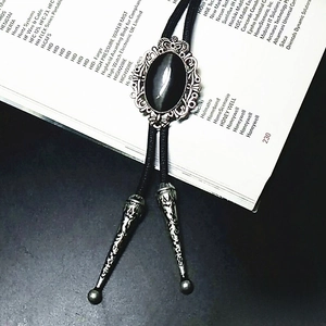 Detail of crown-set black onyx bolo tie with ornate silver frame and metal tips