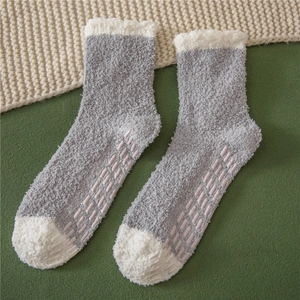 Detail of coral fleece slipper socks featuring non-slip grippers and soft gray-white design