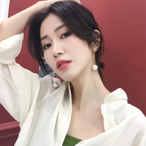 Elegant long gold chain tassel earrings with white pearls worn by a female model
