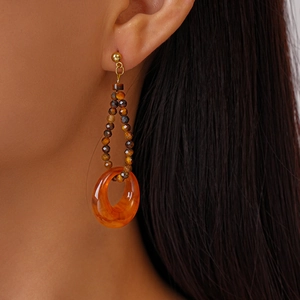 Detail of vintage earring with tiger eye beads and amber resin hoop on model