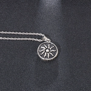 Vue détaillée du pendentif soleil argenté sur une chaîne torsadée avec rayons ondulés