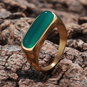 Macro shot of green rectangular gemstone ring on natural wood texture background