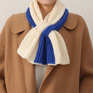 Gros plan d'une écharpe en tricot bicolore beige et bleu portée par un mannequin