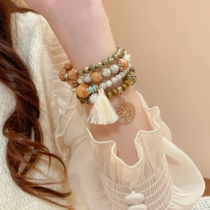 Detail of bohemian multilayer sandalwood beaded bracelet with tree of life charm and tassel