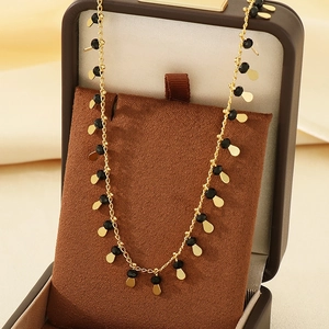 Elegant gold chain necklace featuring black beads and teardrop pendants in a jewelry box