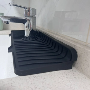 Detail of black silicone faucet draining mat with anti-slip ridges on a kitchen countertop