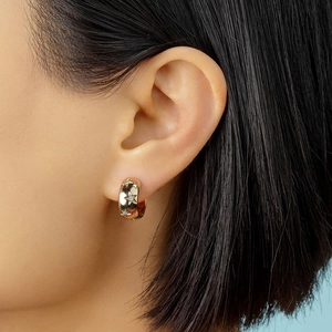 Close-up of golden hoop earring featuring star engravings and inlaid zircons on ear