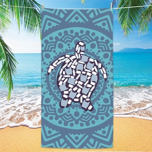 Detail of microfiber beach towel featuring a blue sea turtle mandala design on sand