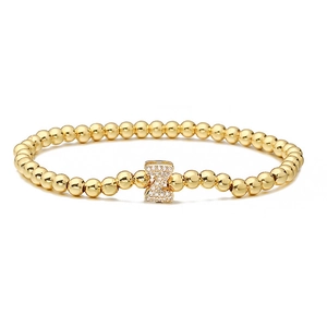 Detailed close-up of golden beaded bracelet featuring a zircon-encrusted letter Z charm