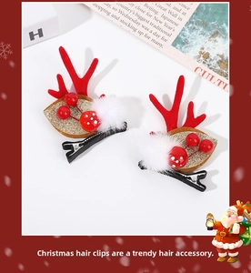 Détail de pinces à cheveux bois de renne rouges avec pompons blancs et baies de Noël