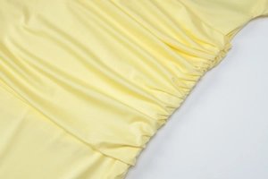 Detail shot of yellow maxi dress featuring side pleats and smooth fabric texture
