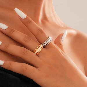 Close-up of lace-textured gold and silver rings with pearls on elegant model hands
