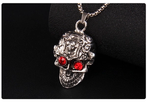Détail du pendentif crâne punk avec yeux en pierres rouges et texture métal argenté