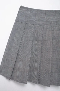 Gros plan sur la texture et les détails du tissu de la jupe plissée pied-de-poule