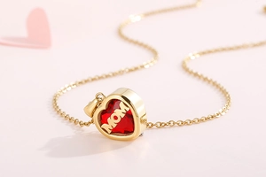 Macro shot of gold heart necklace with MOM lettering and red birthstone detail