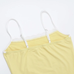 Dettaglio del top a maglia giallo pallido con pizzo bianco e spalline regolabili