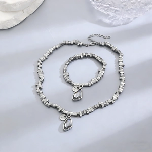 Detail of irregular silver beads and dark teardrop pendants on necklace and bracelet set