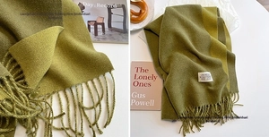 Detail of double-sided cashmere scarf with tassels and stitched label in olive and yellow